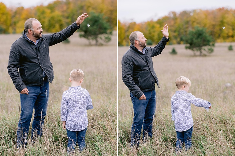 A father drops a dandelion tuft and watches it blow through the air with his son in Petoskey michigan