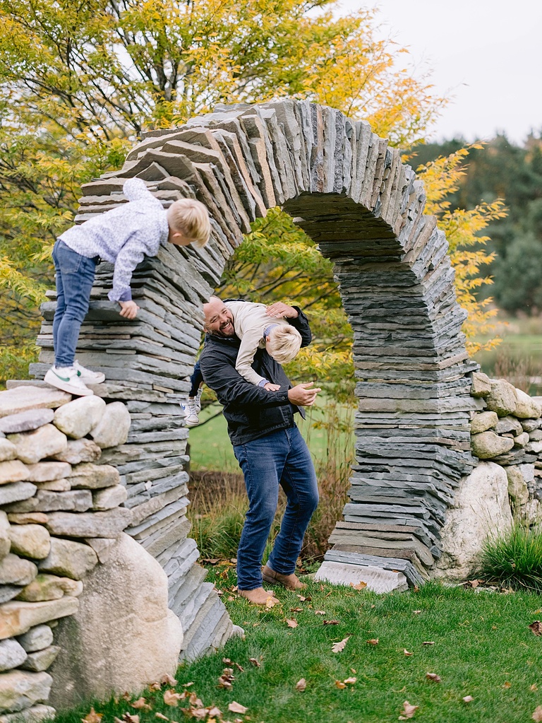 A father laughs while playing with his two young sons near Petoskey michigan in the fall