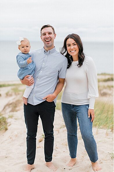 A man and woman pose for Northern Michigan family portraits with their baby girl