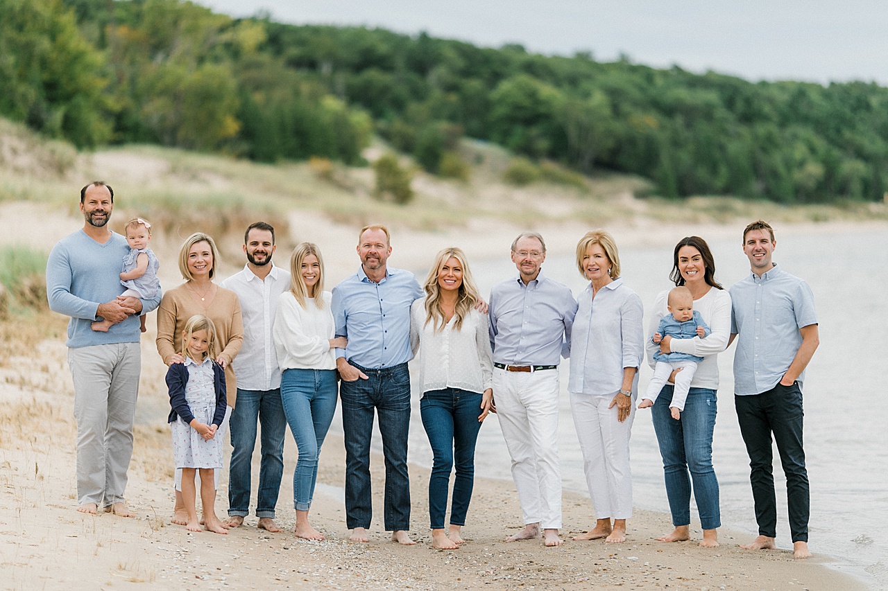 A large family poses together on a Charlevoix beach beside the water