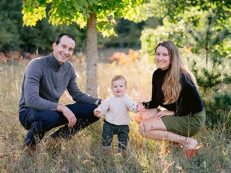 A family of three smiling at the camera during portraits in Traverse City, Michigan