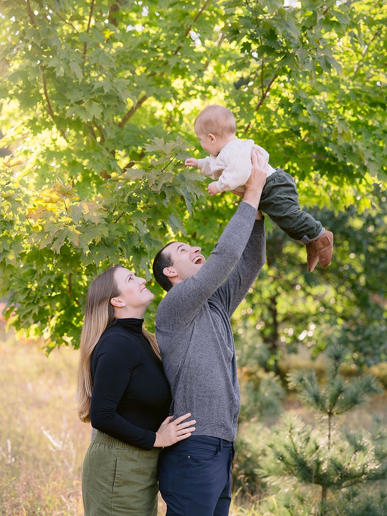 A father lifting up his infant son during a portrait session in October in Michigan