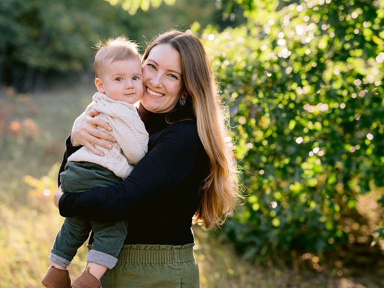 A mother holding her infant son in the sunlight on a beautiful fall day in Old Mission Peninsula, Michigan