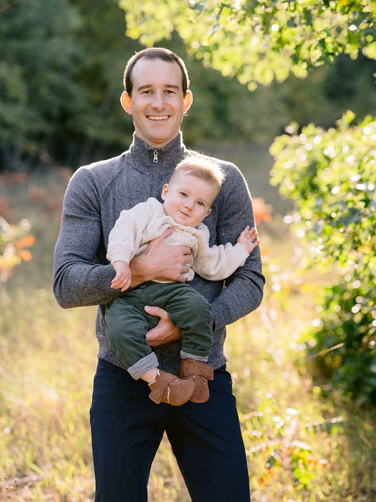 A father and infant sun standing in the autumn sunlight