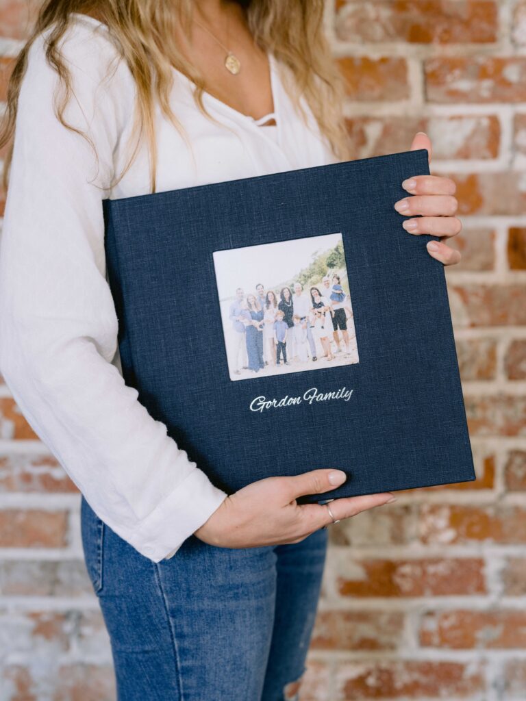Luxury 12x12 navy blue linen family photo album displaying professionally captured Northern Michigan family portraits by the water and outdoors.