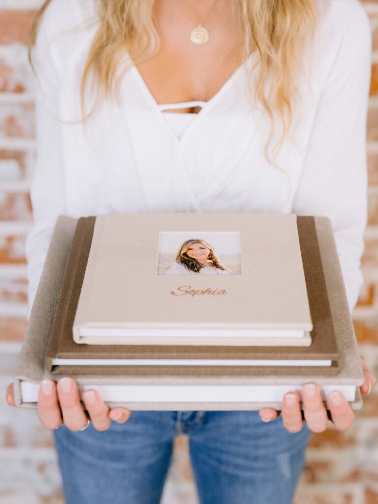 Stacked brown linen family portrait albums in multiple sizes featuring elegant heirloom designs inspired by Northern Michigan family photography.
