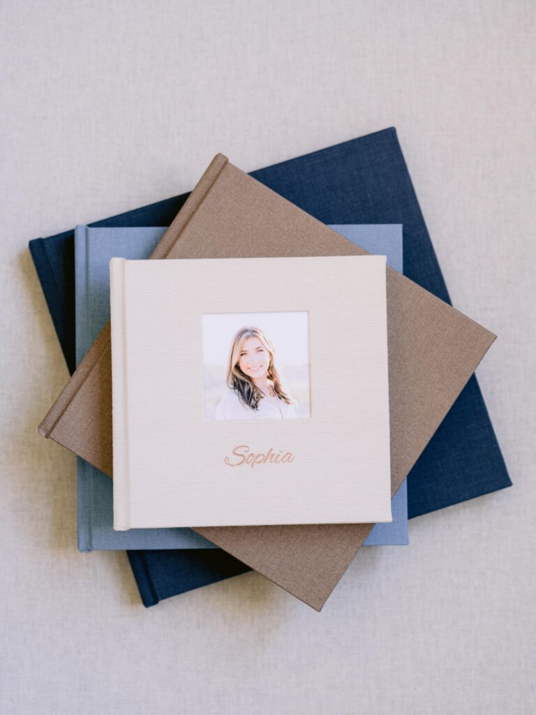 Stacked linen family portrait albums in brown, tan, light blue, and navy blue featuring timeless heirloom designs for Northern Michigan family photography.